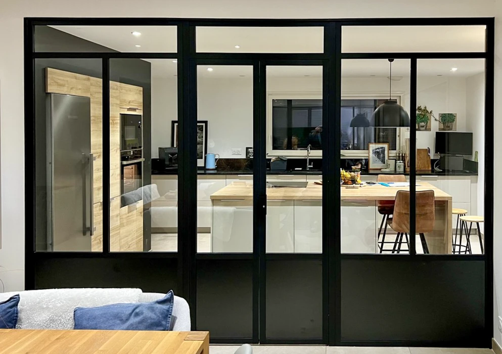 Intérieur moderne avec verrière d'atelier séparant salon et cuisine ouverte