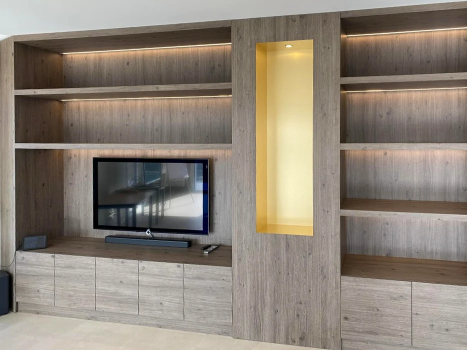 Salon moderne avec meuble TV intégré dans bibliothèque murale en bois naturel