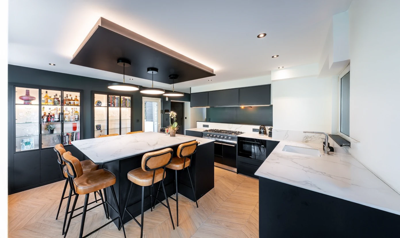 Cuisine moderne avec &icirc;lot central &eacute;quip&eacute; de tabourets hauts, placards en bois naturel et plan de travail en granit