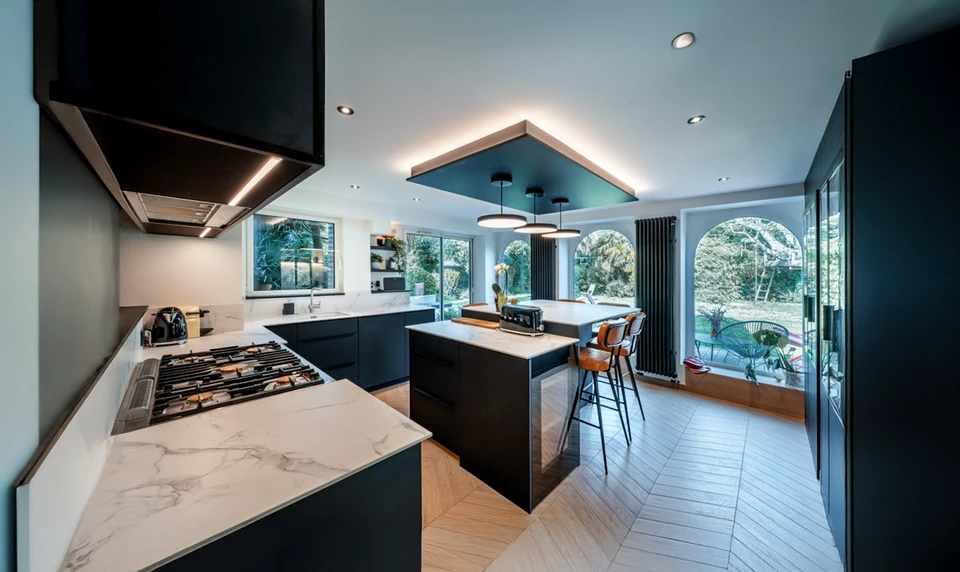 Intérieur d'atelier, homme en chemise bleue travaillant sur table technique, dessinant au crayon sur plans architecturaux détaillés