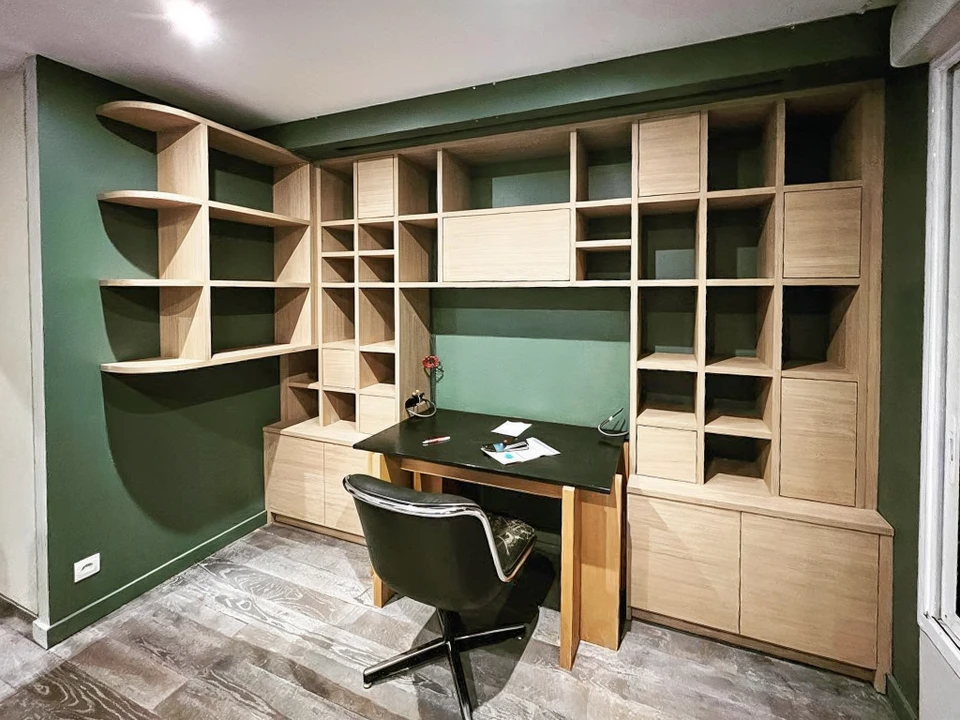 Quatre professionnels souriants collaborent autour d'un ordinateur portable dans un bureau moderne lumineux