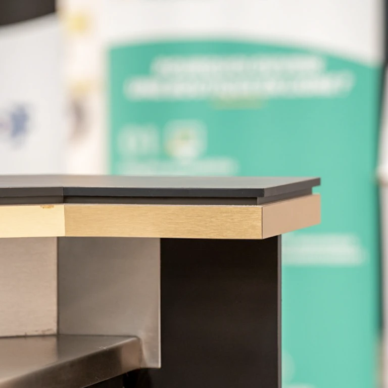 Une main en chemise rayée tient une maquette architecturale détaillée d'un bâtiment de 4 étages avec coupe transversale, révélant l'aménagement intérieur de chaque niveau